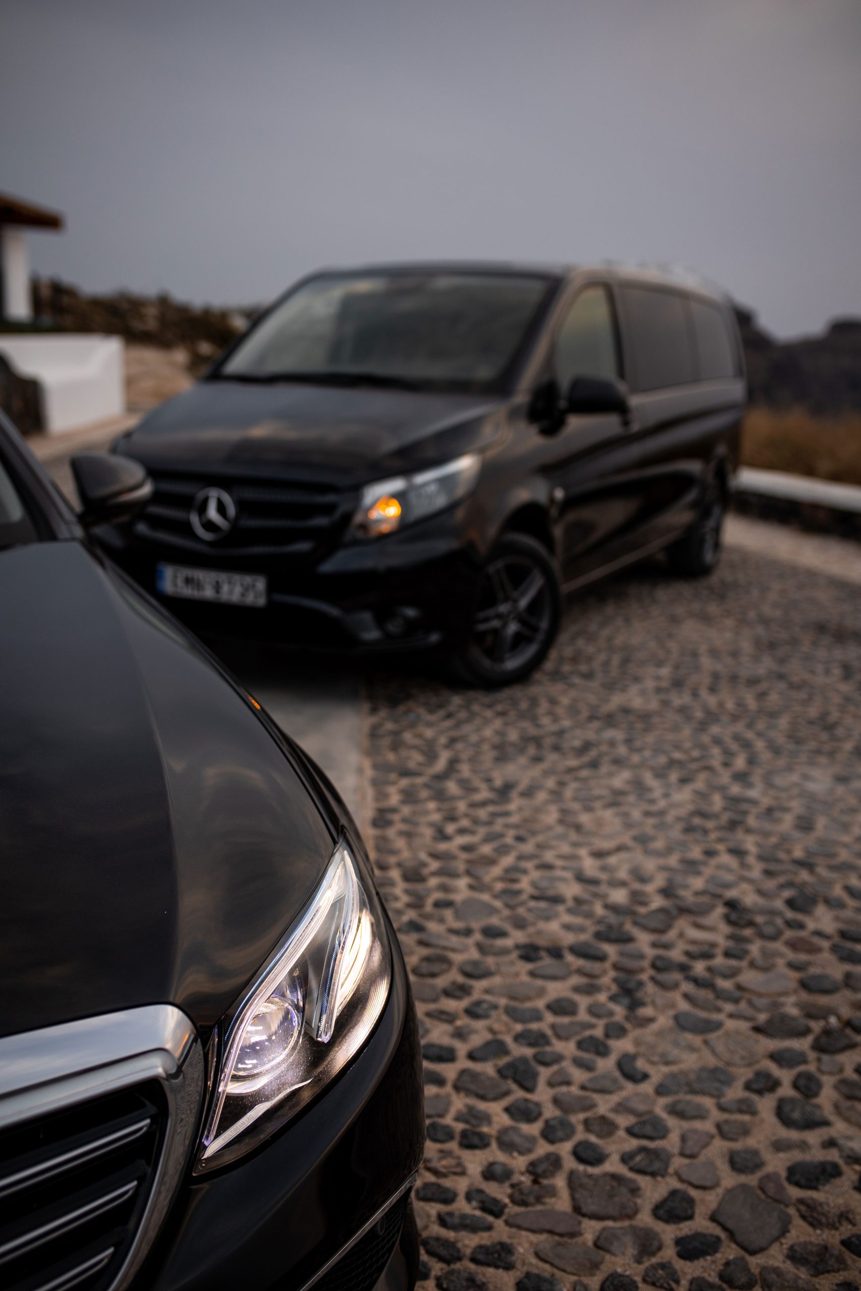 Mercedes-Benz E-Class and Vito transfer van on a Santorini cobblestone drive beside a whitewashed villa