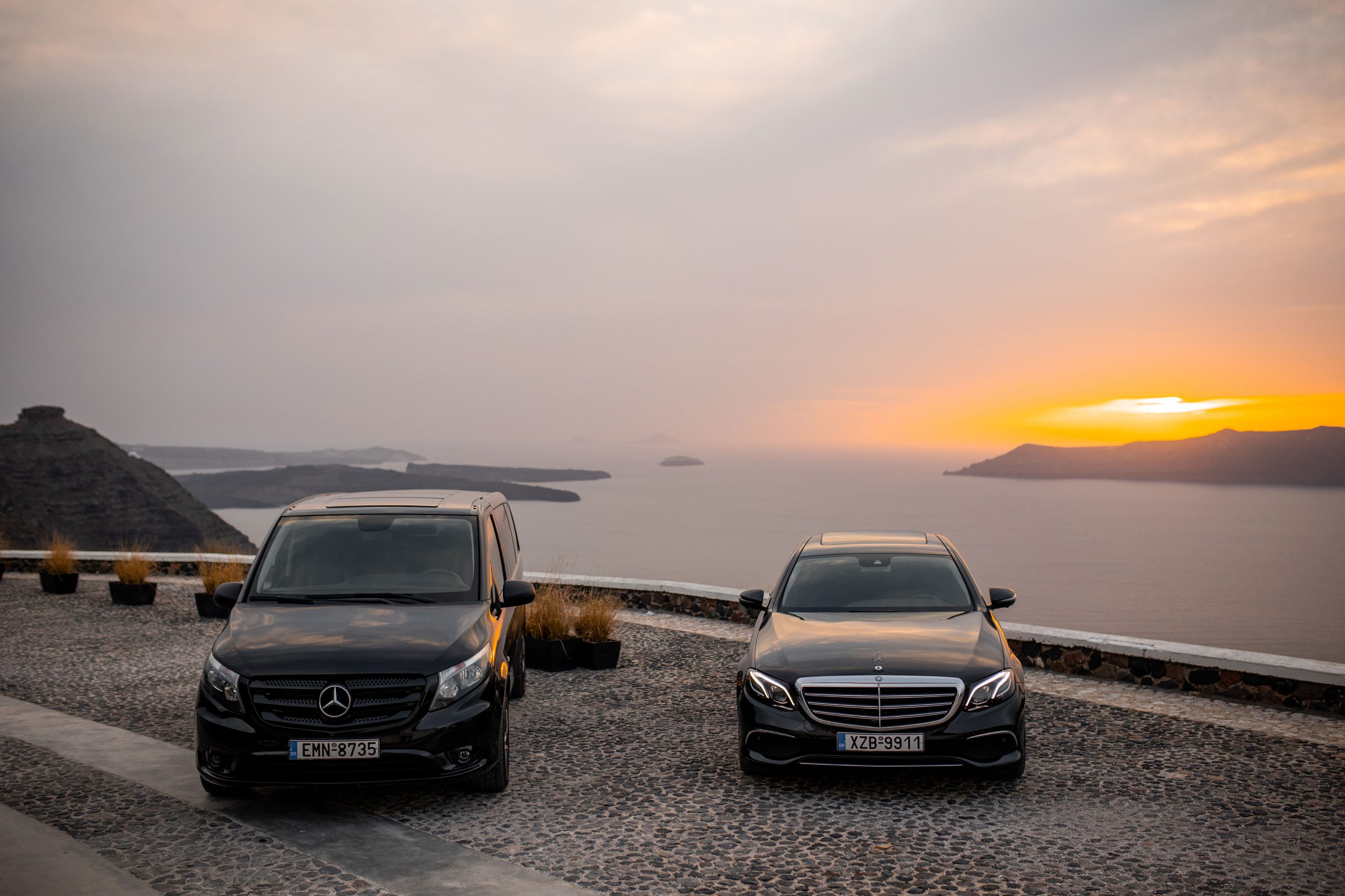 Mercedes-Benz Vito van and E-Class facing the Santorini caldera during a sea sunset