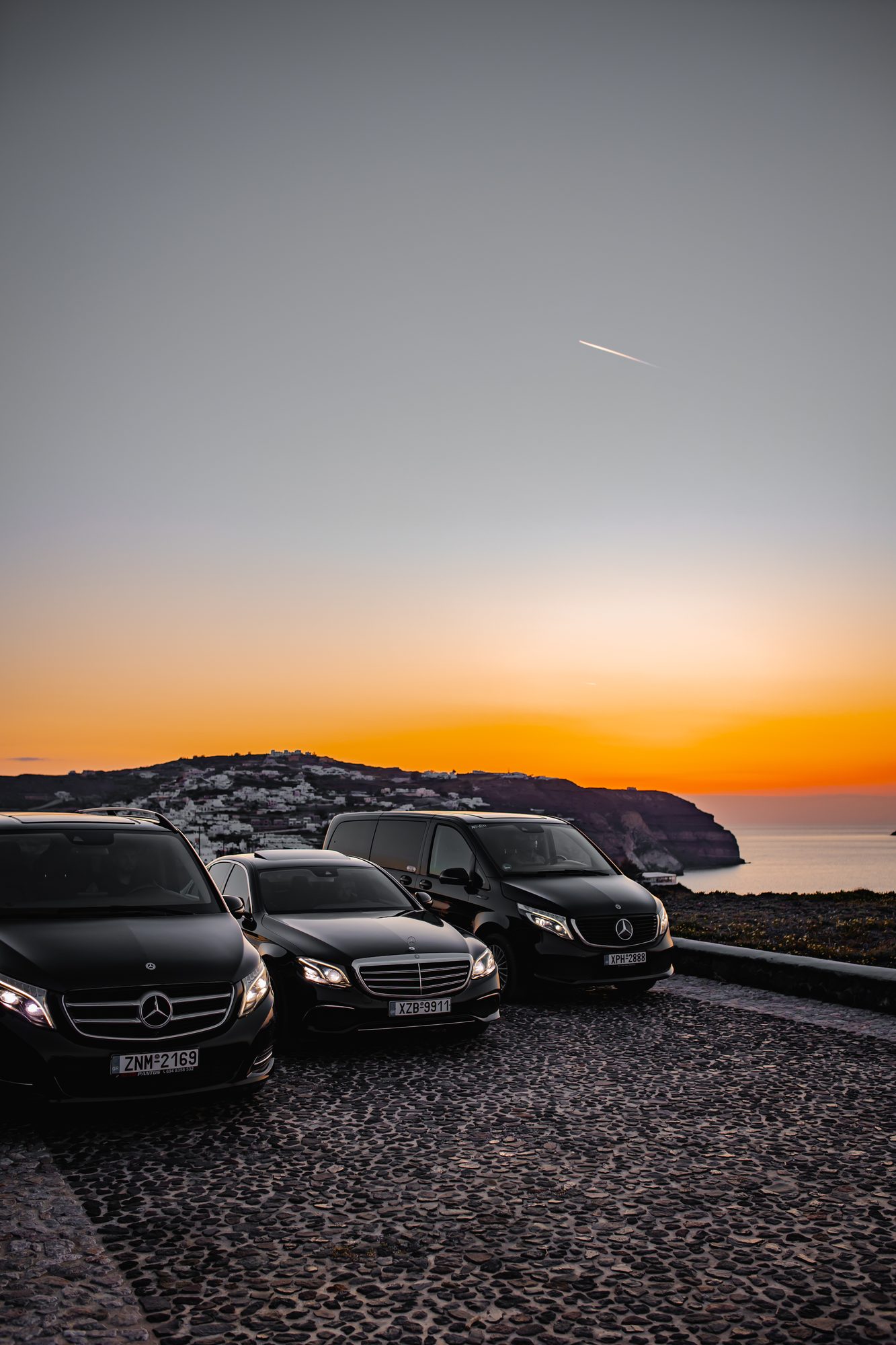 Mercedes-Benz V-Class, E-Class and Vito parked on a cobbled clifftop at sunset in Santorini