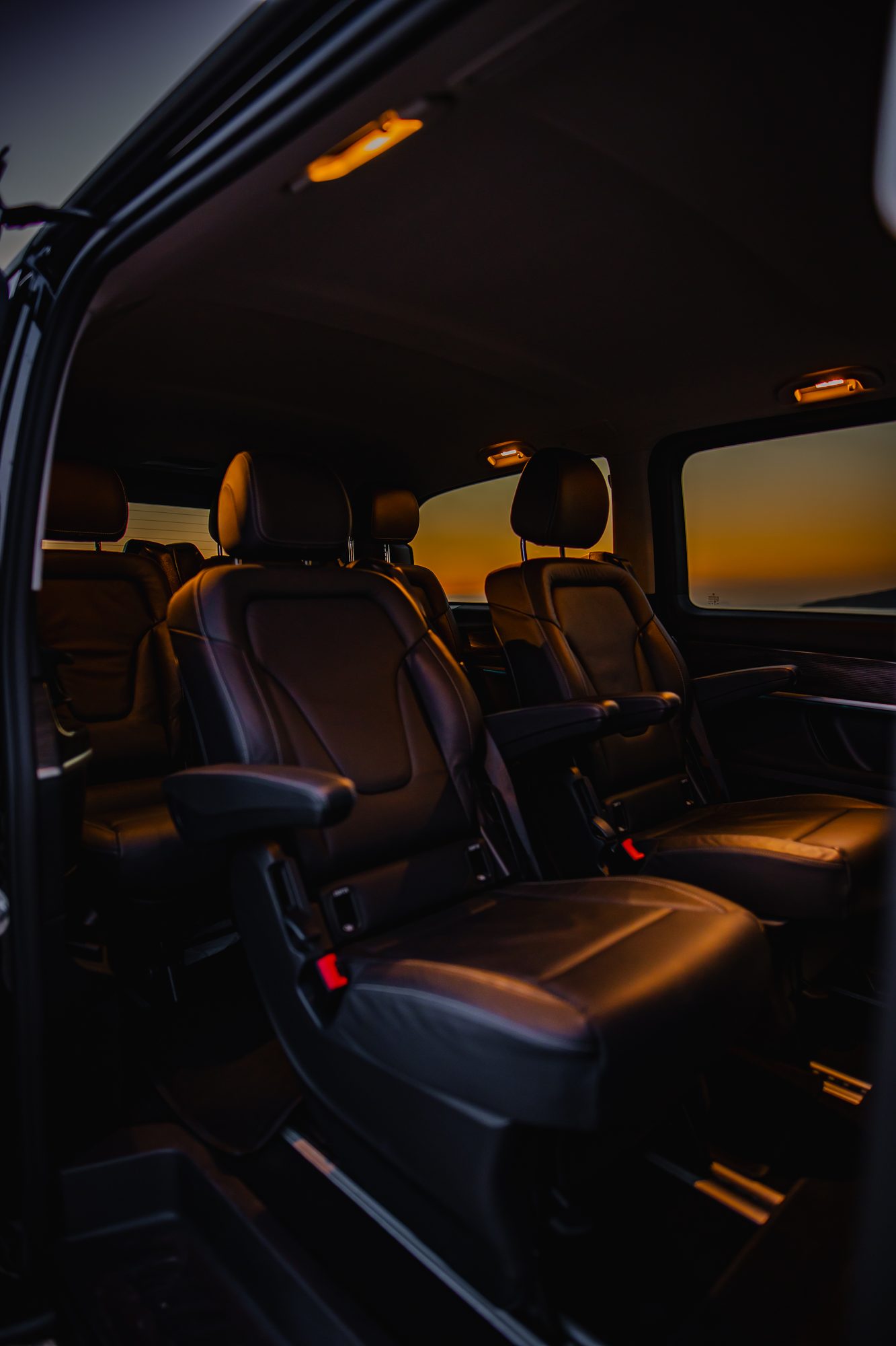 Black leather rear seats of a Mercedes-Benz V-Class van with warm sunset light through the windows